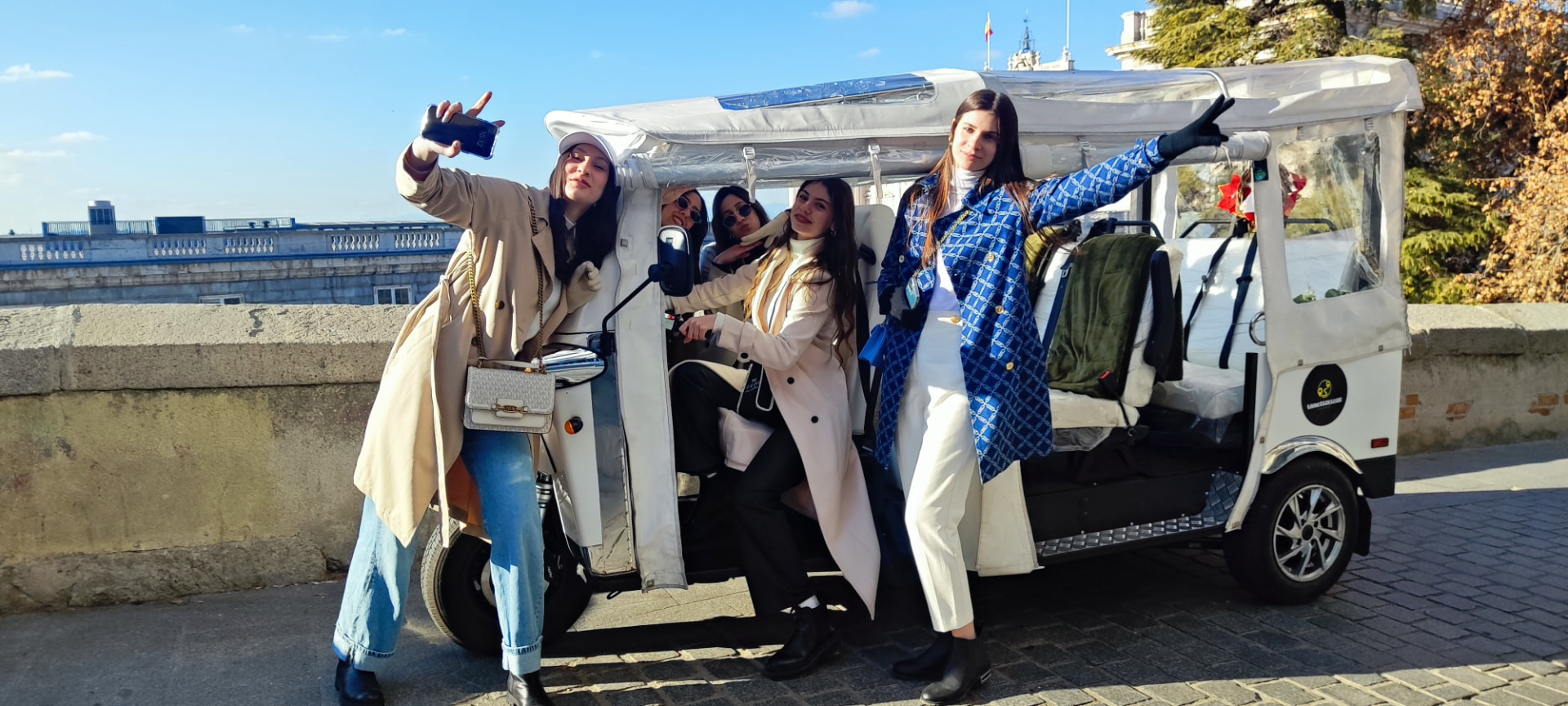 Group of friends posing with a Vamos Tuk Tour tuk-tuk by the Royal Palace